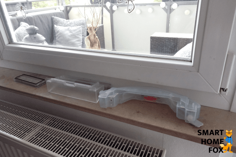 Пылесборник робота-пылесоса сушится на подоконнике после мытья